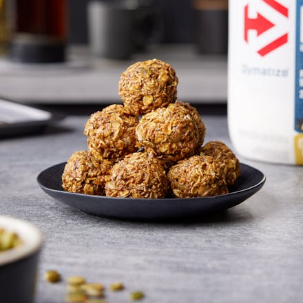 Pumpkin Protein Balls on a counter with a tub of Dymatize nearby
