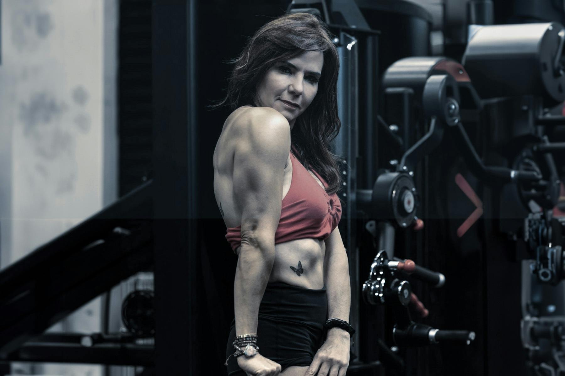 Maria Blacutt flexing her muscles in the gym