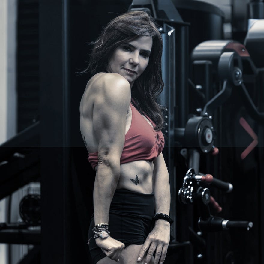 Maria Blacutt flexing her muscles in the gym