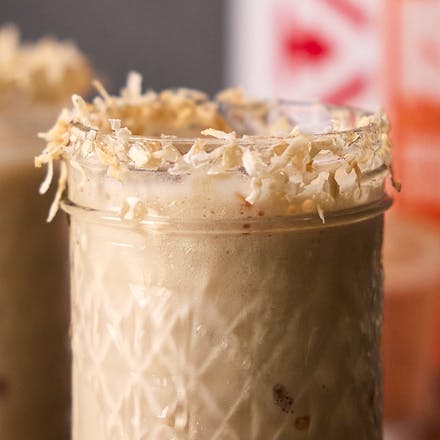 A glass mug filled with Iced Coconut Protein Cappuccino Flavored Drink.
