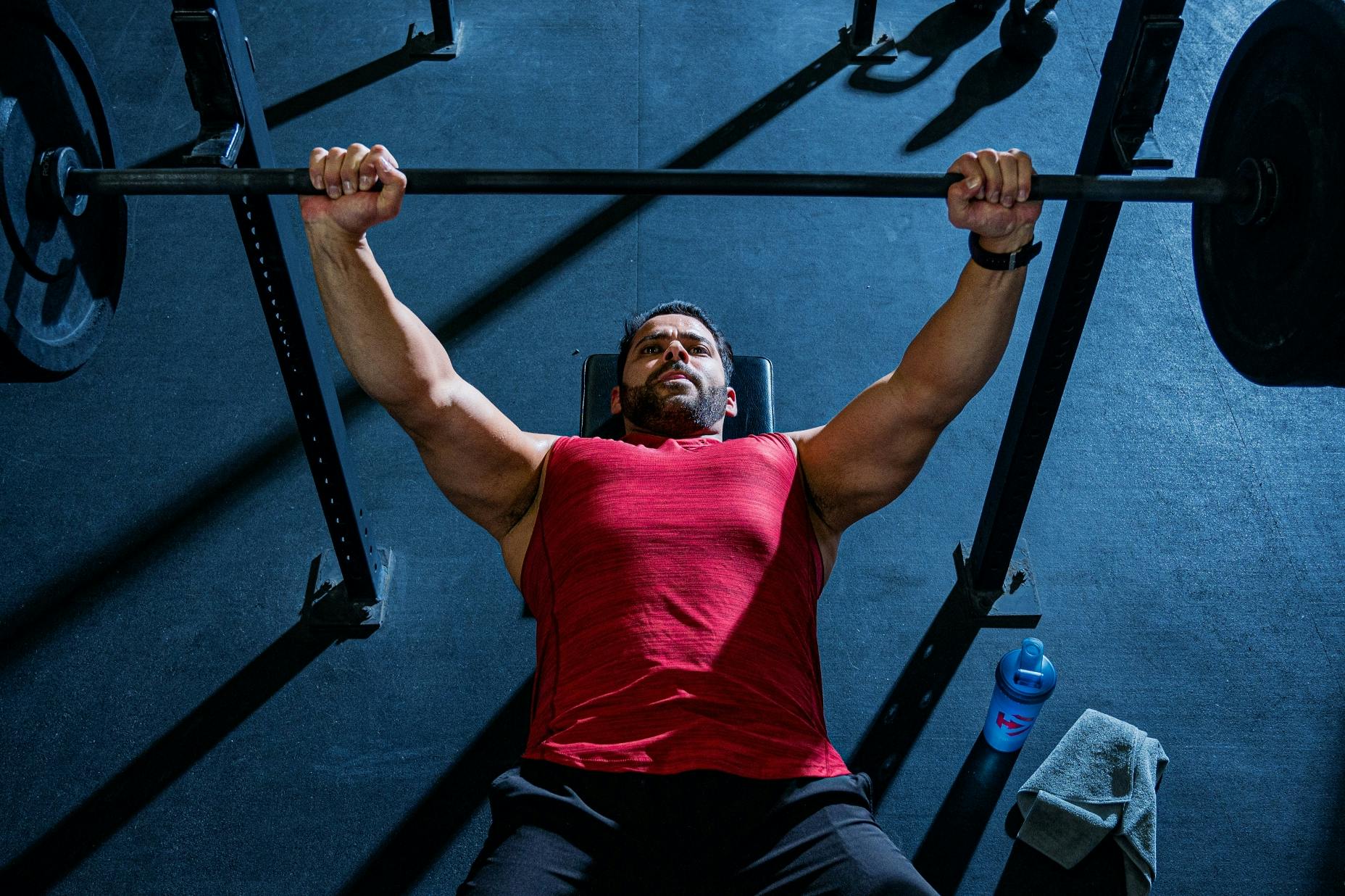 A man laying on his back on a weightlifting bench, lifting some weights.