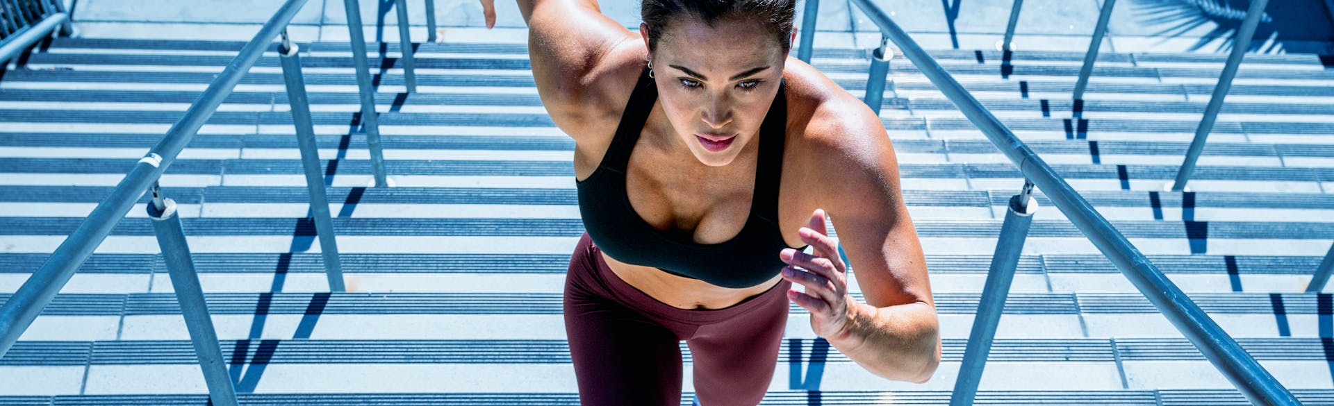 A woman in exercise gear, running up stadium steps.